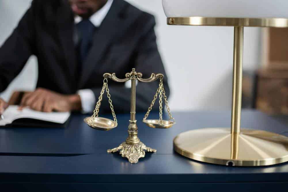 Justice symbolized by scales and a man working in the background